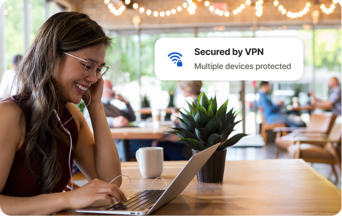 Kvinna på ett kafé skrattar åt skärmen på en laptop