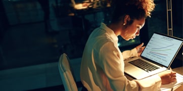 En kvinna sitter framför en bärbar dator